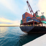 Iran Heroin Pipeline Exposed in Poland Cargo ship loaded with colorful shipping containers at a dock