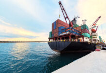 Iran Heroin Pipeline Exposed in Poland Cargo ship loaded with colorful shipping containers at a dock