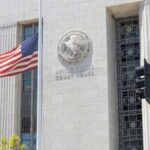 United States courthouse facade with American flag at half-mast