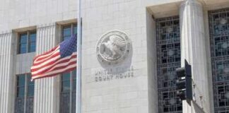 United States courthouse facade with American flag at half-mast
