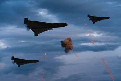 2656305537-1 Three military drones fly through a cloudy sky amid anti-air fire