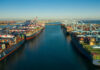 New Tariff Blitz — What’s the Real Agenda? Aerial view of cargo ships docked at a shipping port