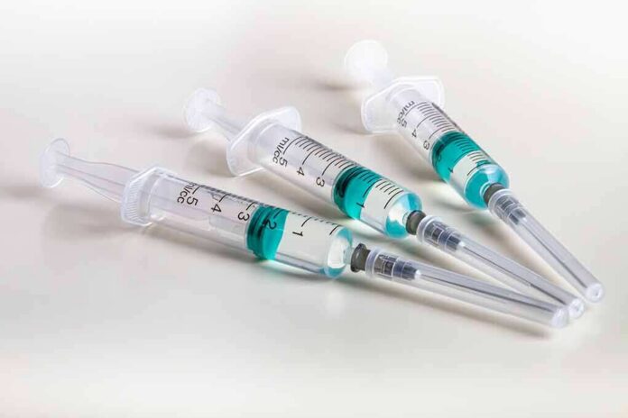 shutterstock_1023268120 Three syringes filled with blue-green liquid on a white surface