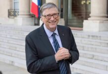 smiling older man in a suit standing on stone steps