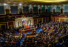 Congress Gambles Voting Rights For $95B A large gathering of officials in a congressional chamber during a legislative session