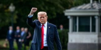 A political figure walking outdoors with a raised fist