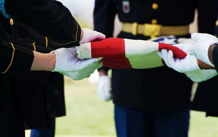 Honor,Guard,At,Arlington,National,Cemetery,Folding,Flag,Over,Casket Military personnel folding a flag during a ceremonial event