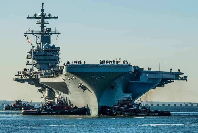 shutterstock_1018972291-1 Aircraft carrier guided by tugboats in a harbor