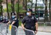 Police officers in masks standing by metal barricades outdoors
