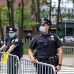 Police officers in masks standing by metal barricades outdoors
