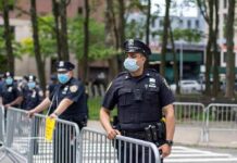 Five-Hour Silence Topples Seattle Chief Police officers in masks standing by metal barricades outdoors