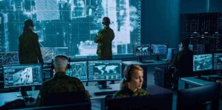 Military analysts monitor data on multiple screens in a command center