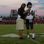 football coach with arm around player number 84 on sideline