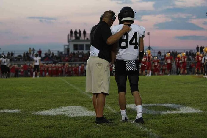football coach with arm around player number 84 on sideline
