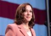 woman speaking at podium with flag backdrop