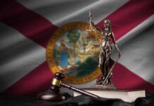 Lady Justice statue with gavel and book before Florida state flag