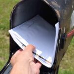 Hand retrieving mail from an open rural mailbox