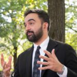 Teacher Endorsement Explodes — City Hall Meltdown Man in a suit gesturing while speaking outdoors