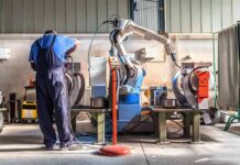 Royal Navy’s Costly Ghost Ship Factory worker operates near an industrial robot arm in a workshop