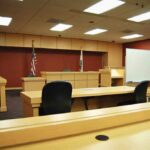 Interior view of an empty courtroom with wooden furniture and American flags