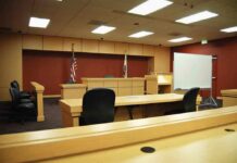 Judges Torpedo Cash Punishment For Publishing Interior view of an empty courtroom with wooden furniture and American flags