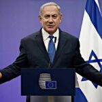 Hamas Jab Sparks Turkey Flashpoint man in suit speaking at a podium with Israeli flag