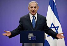 Hamas Jab Sparks Turkey Flashpoint man in suit speaking at a podium with Israeli flag