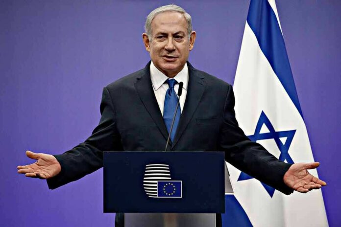 shutterstock_1046491414 man in suit speaking at a podium with Israeli flag