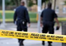 Domestic Homicide Shock in Illinois Police officers walking past caution tape at a crime scene