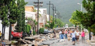 Residents walk along a heavily damaged street after a disaster