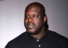 Shaquille O'Neal in a black polo shirt looking to the side