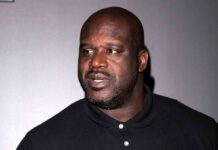Shaquille O'Neal in a black polo shirt looking to the side