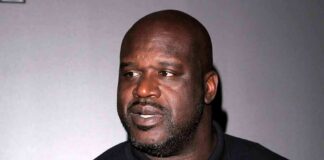 Shaquille O'Neal in a black polo shirt looking to the side