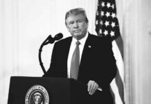 Donald Trump at a podium with microphone and U.S. flag in background