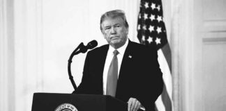 Donald Trump at a podium with microphone and U.S. flag in background