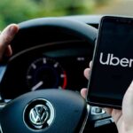 Driver holding smartphone with Uber app inside Volkswagen