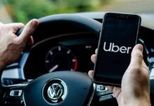 Driver holding smartphone with Uber app inside Volkswagen