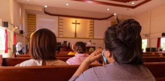 people seated in church pews facing a cross