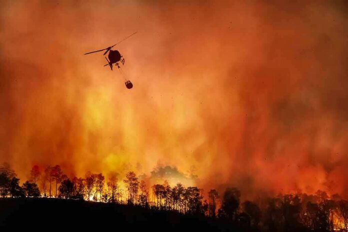 shutterstock_1810018291 Helicopter fights massive wildfire over burning forest