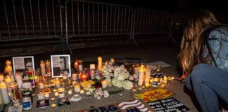 Vigil with candles and signs on a sidewalk at night