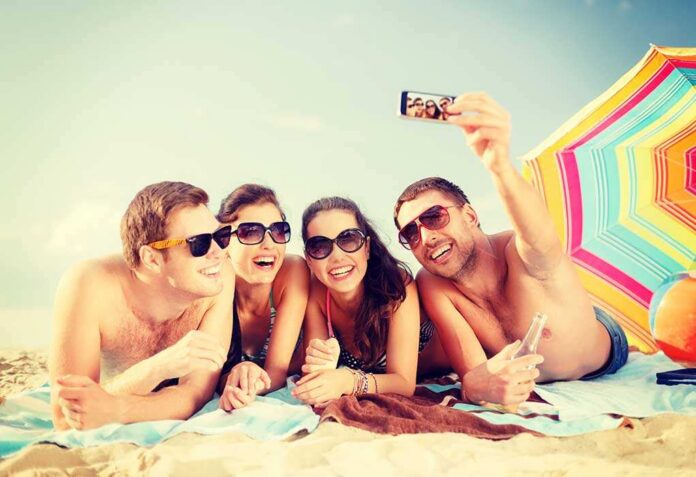 Summer,,Holidays,,Vacation,,Technology,And,Happiness,Concept,-,Group,Of Group of friends taking a selfie on the beach