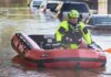 Coastal Floods Surge – Jersey Homes Hit Rescue worker in an inflatable boat during urban flooding