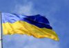 Ukrainian flag waving on a flagpole against blue sky