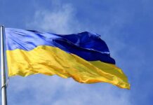 War Swallows Ukraine’s Economy Ukrainian flag waving on a flagpole against blue sky