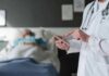 Doctor Fined After Puberty Blocker Refusal Doctor using tablet beside hospital patient