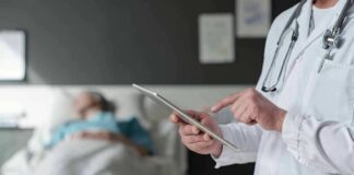 Doctor using tablet beside hospital patient