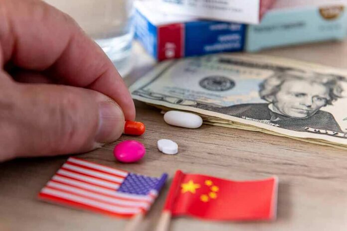 shutterstock_2336322065 Hand picking an orange pill beside US and China flags and cash
