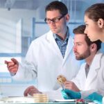 Scientists in lab coats reviewing data on a computer