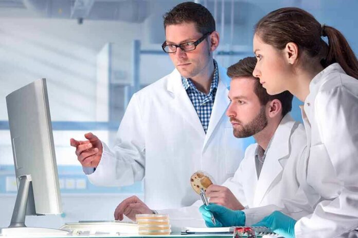 shutterstock_267953705 Scientists in lab coats reviewing data on a computer