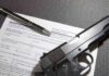 Handgun on firearm transaction form with pen